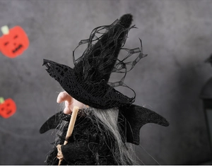 Détail d'une poupée de sorcière d'Halloween avec chapeau en dentelle et balai en bois