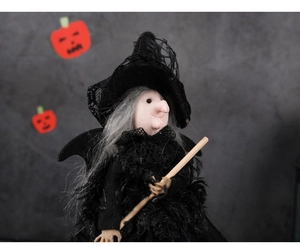 Détail de la poupée de sorcière d'Halloween avec dentelle noire, plumes et balai