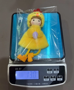 Pendentif poussin de Pâques avec œuf violet sur une balance pesant 13 grammes