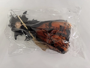 Détail de poupée sorcière d'Halloween avec jupe orange et balai de paille sous emballage