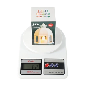 Macro weight measurement of an LED castle lantern showing 62g on a white scale