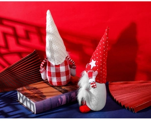 Detailed view of two Christmas gnome plush dolls on a festive red background with props