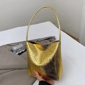 Vue détaillée de la texture crocodile dorée et de la finition brillante du sac seau