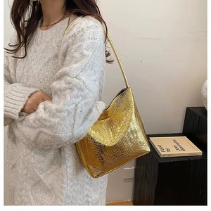 Détail d'un sac à bandoulière doré métallisé avec texture façon crocodile