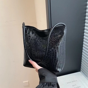 Détail de la texture motif crocodile noir et finition brillante de ce sac à main