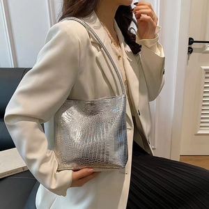 Détail d'un sac cabas argenté motif crocodile montrant la texture sur une épaule