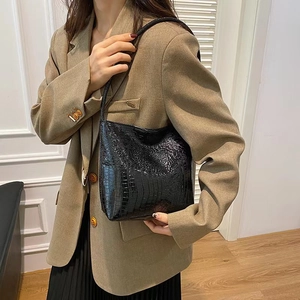 Détail de la texture crocodile noire et finition brillante sur ce grand sac fourre-tout