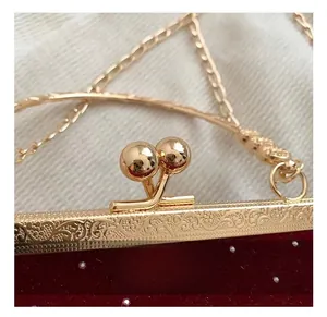 Macro detail of vintage gold kiss-lock clasp with European floral engravings on a red velvet bag