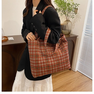 Detailed view of a multi-color plaid tote bag styled with a chic black blazer outfit