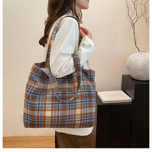 Detailed view of the large plaid tote bag worn on shoulder showing its size and texture