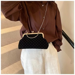 Model wearing a black velvet evening clutch bag with pearl bead accents and gold chain