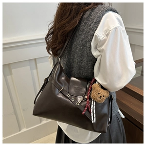 Side view of deep brown vintage tote bag with metal eyelets and plush bear charm