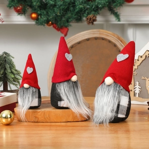 Trois gnomes de Noël suédois avec bonnets rouges et cœurs gris sur décor de table bois