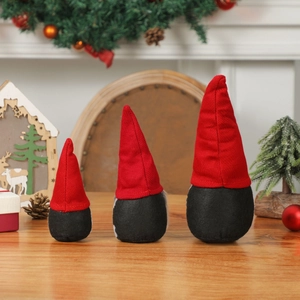 Lot de trois gnomes de Noël en rouge et noir sur une table festive en bois