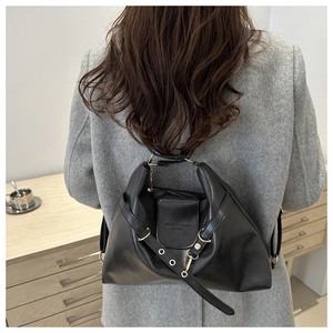 Close-up of a vintage black leather backpack showing the metal ring detail and strap