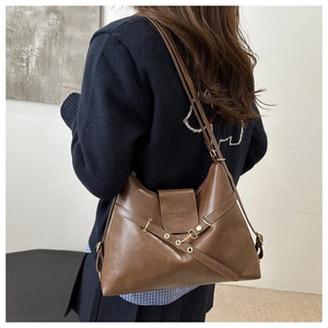 Close-up of vintage brown leather tote bag with stylish lacing and gold metal buckles