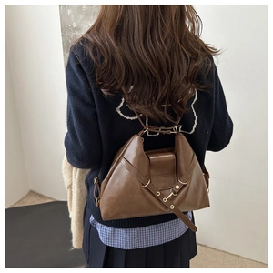 Detailed view of dark brown leather texture and metal buckle accents on a vintage tote bag
