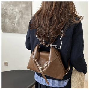 Detail of dark brown vintage leather tote showing buckle strap and embossed text logo