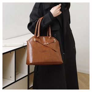 Braune Leder-Einkaufstasche mit Metalldetails in einer stilvollen Innenaufnahme gezeigt
