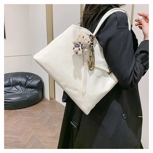 Detail der weißen Leder-Shopper-Tasche mit langen Trägern und süßem Plüschtier-Anhänger