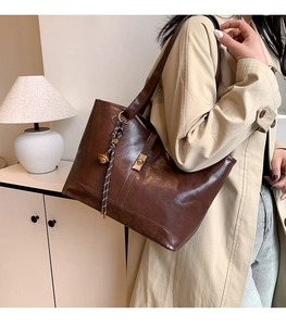 Détail du grand sac cabas marron foncé avec breloque tressée et boucles dorées chic