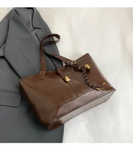 Détail de la texture d'un sac cabas en cuir marron avec fermoir et pendentif tissé