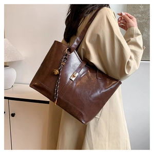 Détail d'un cabas en cuir vintage marron foncé avec fermoir rotatif et breloque latérale