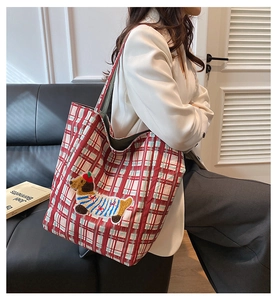 Detail of red plaid canvas tote bag with cute dog embroidery shown on model