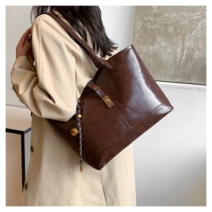 Détail du sac cabas marron foncé en cuir huilé avec fermoir métal et breloque cloche