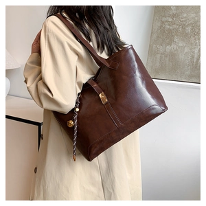 Détail du grand sac cabas marron foncé brillant avec boucle dorée sur le mannequin