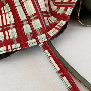 Close-up of high-quality stitching on the red and green plaid canvas tote bag strap