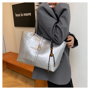 Détail du sac cabas argenté métallisé avec fermoir doré et pendentif tressé élégant