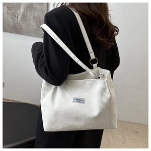 Detail of white corduroy tote bag showing ribbed texture and fashion logo label