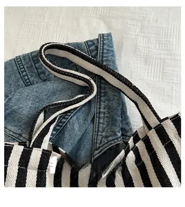 Detail of the durable handle attachment on a black and white striped canvas tote bag