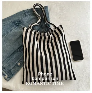 Detailed view of striped canvas tote bag showing large capacity with phone size comparison