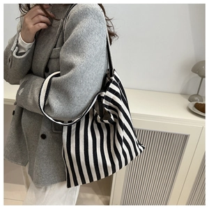 Detailed view of striped canvas tote bag worn on shoulder for daily commute style