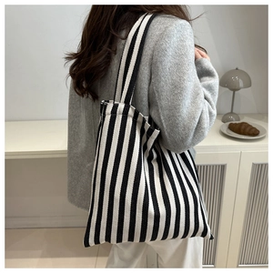 Detailed side view of large canvas tote bag featuring black and white vertical stripes