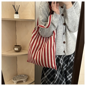 Detail of red and white striped canvas tote bag held by a model in a minimal lifestyle setting