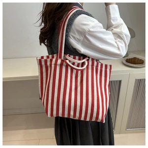 Detail of red and white striped canvas tote bag showing woven texture and dual handles