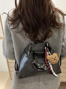 Vintage black leather tote bag with bear charm and silk scarf on grey coat model