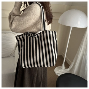 Detailed close-up of a large black and white striped canvas tote bag worn on shoulder