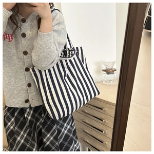 Detailed view of a blue and white striped canvas tote bag in a casual lifestyle setting