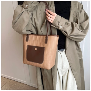 Detail einer großen Khaki-Braun gesteppten Tragetasche mit Druckknopftasche am Modell