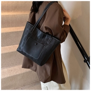 Detail einer schwarzen gewebten Shopper-Tasche mit weißen Kontrastnähten und Druckknopftasche