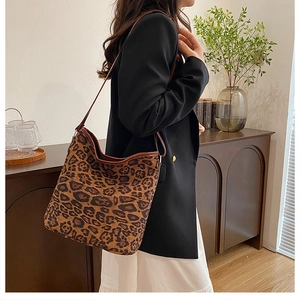 Dettaglio della grande borsa tote leopardata con finiture in pelle marrone indossata a spalla