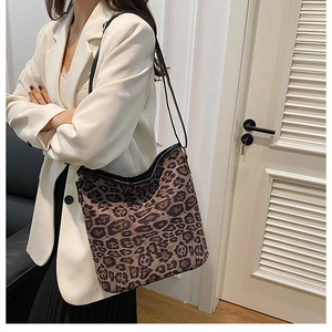 Modella che indossa una borsa a spalla scamosciata leopardata con tracolla nera