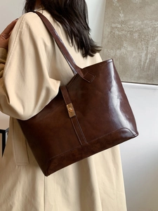 Sac fourre-tout marron rétro en cuir huilé porté par un mannequin à l'épaule