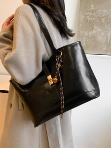 Grand sac cabas noir en cuir avec boucle dorée et pompon rayé pour le shopping quotidien
