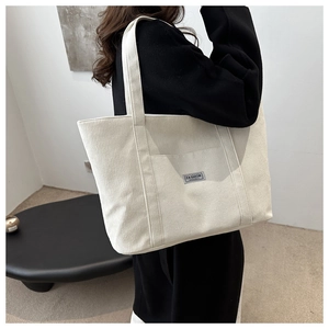 Off-white corduroy tote bag shown on shoulder featuring soft texture and fashion label
