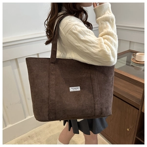 Detailed close-up of brown corduroy tote bag featuring a white Fashion Instinct label